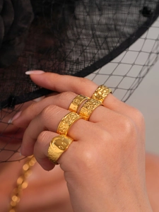Set of five vintage gold rings with smiley face and textured designs on a hand
