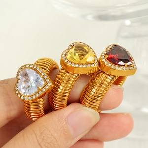 Three gold spiral rings with colorful heart gems worn on fingers in a professional set