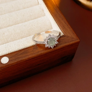 Close-up of vintage flower ring with green stone and pavé zircons on a wooden jewelry box