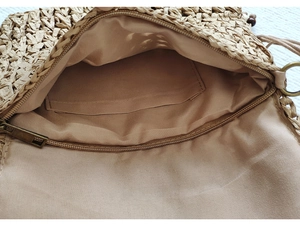 Detail view of woven straw bag interior with khaki fabric lining and metal zipper closure