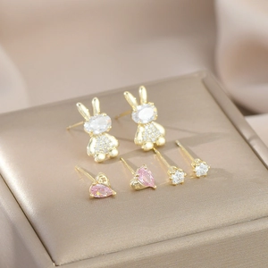 Detail view of 3-pair earring set featuring golden rabbits and pink heart zircons