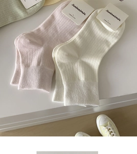 Detailed close-up of ribbed texture and branded tags on pink and cream cotton socks