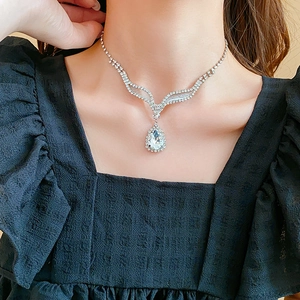 Détail du collier argenté en V avec pendentif en strass en forme de poire sur cou