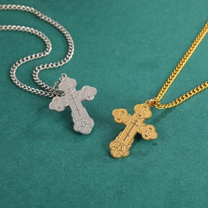 Detail of gold and silver Orthodox cross necklaces with IC XC engravings on green surface
