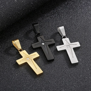 Detailed shot of three stainless steel cross pendants in gold, black, and silver finishes