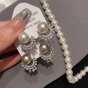 Macro shot of elegant silver needle earrings featuring large pearls and zircon tassels