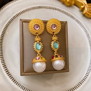 Vintage gold earrings with purple gemstones and white pearl drops on a classic jewelry box