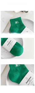 Detail view of green cotton socks featuring white NA embroidery and reinforced toe