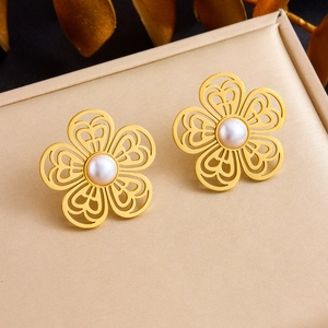 Golden hollow flower earrings with central pearl on jewelry box, elegant floral jewelry set
