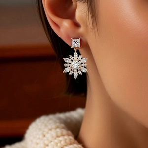 Close-up of 14k gold plated snowflake drop earrings with zircons worn by a model