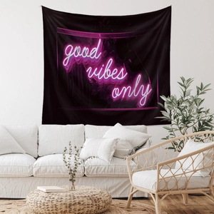 Detail of neon-style Good Vibes Only text on black tapestry in a cozy room decor