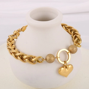 Golden heart pendant chain bracelet with matte beads displayed on a white vase