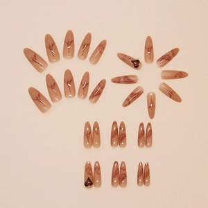 Detail of long stiletto press-on nails with marble texture and 3D heart decorations