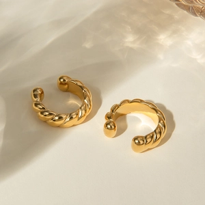 Detail shot of 18k gold plated twisted rope clip-on earrings on a beige surface