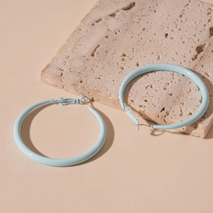 Close-up of light blue geometric hoop earrings on a textured stone display pedestal