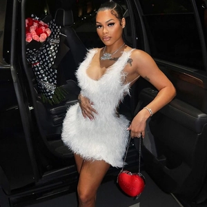 Detail of white feather mini dress with red heart-shaped handbag in elegant night street style