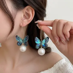 Elegant gold earrings with blue butterfly pendants and iridescent pearls for women