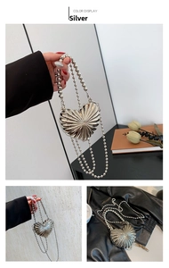 Detail of silver heart-shaped metal bag with radial texture and beaded chain strap