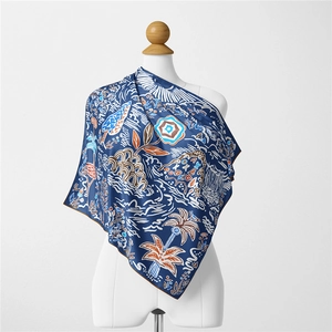 Detailed pattern of tropical palm trees and floral motifs on a blue silk scarf