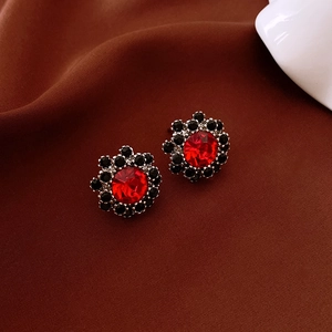 Detail of vintage flower earrings with red and black crystals on brown silk