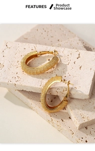 Close-up of golden frosted hoop earrings with textured finish and buckle clasp