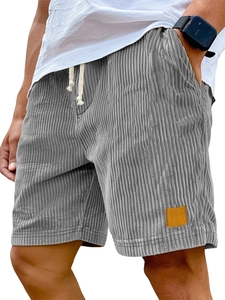Macro detail of men's grey corduroy shorts showing textured fabric and leather patch