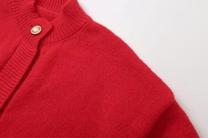 Detailaufnahme der roten Strickjacke mit feiner Textur und Metallic-Knöpfen