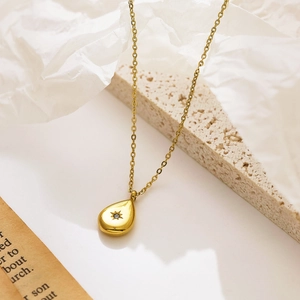 Détail d'un collier doré avec pendentif goutte d'eau et zircon sur un support rocheux