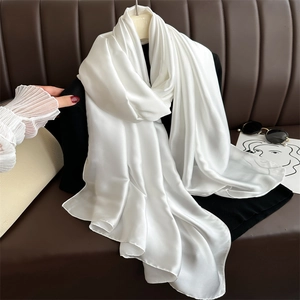 Detailed texture of a white satin scarf draped elegantly over a leather sofa setting