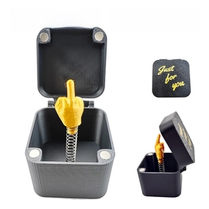 Macro view of a 3D-printed middle finger prank box with gold gesture and spring