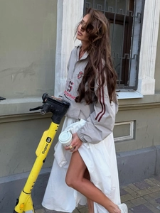 Outdoor lifestyle shot of a retro grey sports windbreaker and long white flowy skirt
