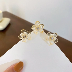 Detailed macro view of three white floral hair claws with centered sparkling rhinestones