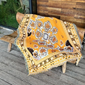 Macro view of bohemian woven blanket featuring yellow paisley patterns and decorative tassels