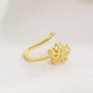 Macro detail of gold flower non-pierced nose ring with micro-paved zircons on silk