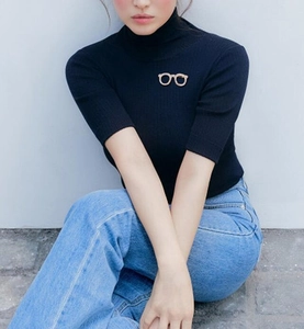 Close-up of a gold glasses brooch with sparkling rhinestones on a navy knit sweater