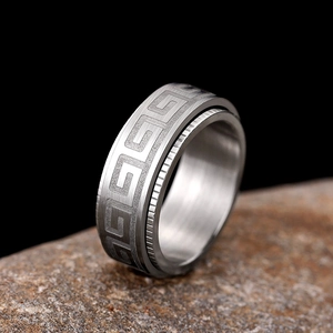 Macro shot of silver stainless steel ring with Greek meander pattern on rustic rock