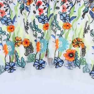 Elegante ricamo floreale su abito in rete bianca con motivi floreali arancioni e blu vivi