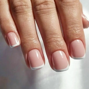 Close-up of classic French manicure with nude pink base and white square tips
