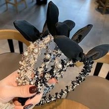 Detail of tweed hair claws with elegant pearls and black bows in hand-held close-up