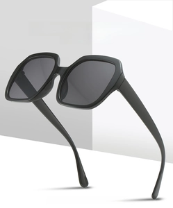 Detail view of large polygon sunglasses featuring high definition grey lenses and black frames