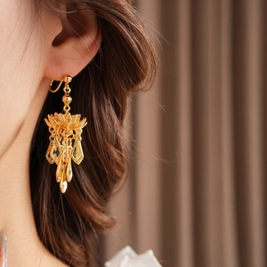 Close-up of vintage gold lotus leaf tassel earring worn by a model in soft lighting