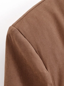 Close-up of shoulder stitching and woven fabric texture on a coffee brown blazer
