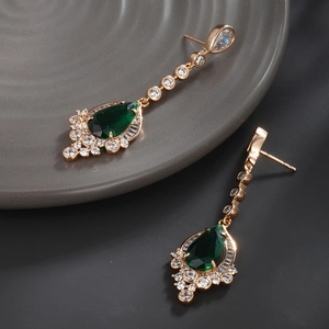 Macro shot of vintage teardrop emerald earrings with micro-pave crystals in gold finish