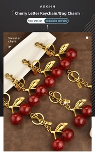 Flat lay of cherry keychains with letter charms, red glitter finish and golden leaf detail