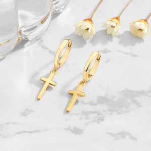 Detail showing S925 hallmark on gold-plated cross hoop earrings over marble surface