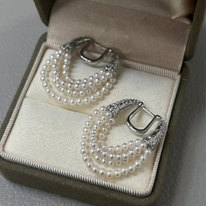 Close-up of multi-layer pearl horseshoe tassel earrings with zircon in a beige jewelry box