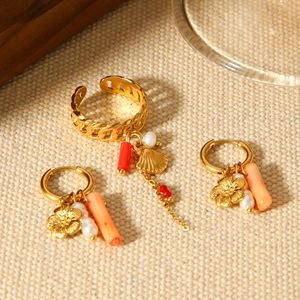 Detail of gold floral earrings and ring set with coral beads and pearls on beige fabric