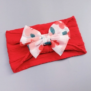 Close-up of red cable knit baby headband with white floral print bow detail