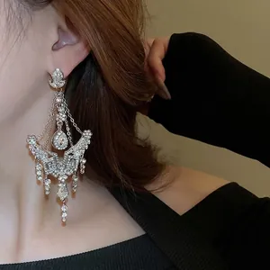 Elegant silver flower drop earrings with shimmering rhinestone tassels on a model
