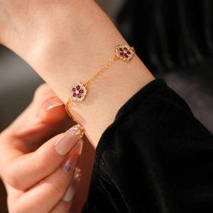 Detail of 18k gold plated flower bracelet with ruby-red stones and white zircon crystals